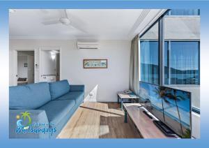 a living room with a blue couch and a flat screen tv at Marina views at Airlie 10H in Airlie Beach
