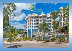 a building with palm trees in front of a street at Marina views at Airlie 10H in Airlie Beach