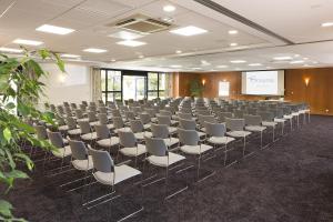 una sala de conferencias con filas de sillas y una pantalla en Oceania Rennes, en Saint-Grégoire