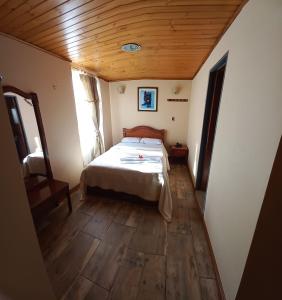 Hotel Buenaventura في باستو: غرفة نوم بسرير وسقف خشبي