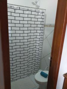 a bathroom with a toilet and a white brick wall at Casa com vista para o mar em Paraty in Paraty