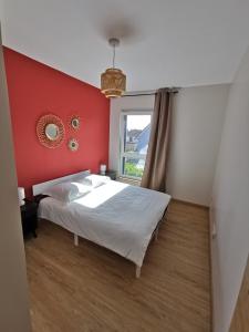 ein Schlafzimmer mit einem Bett mit einer roten Wand in der Unterkunft Maison moderne et accueillante in Mackenheim