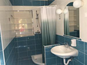 a blue tiled bathroom with a sink and a toilet at Apartments MiaMaja in Novalja