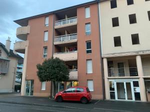 une voiture rouge garée devant un bâtiment dans l'établissement [Le Bohème] T2-Wifi-Calme-Parking, à Lourdes