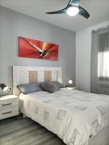 a bedroom with a white bed with a painting on the wall at Casa junto al mar in Blanes