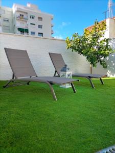 two benches sitting on the grass near a building at Casa junto al mar in Blanes