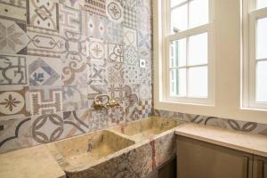 baño con lavabo y pared de mosaico en Bendi Guest House Blue Experience, en Sintra