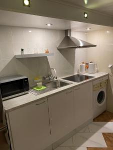 a white kitchen with a sink and a microwave at Guest House Vilnius in Vilnius