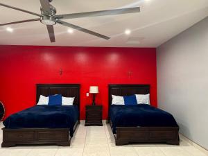 two beds in a room with a red wall at Casa de campo con vistas espectaculares in Nogales