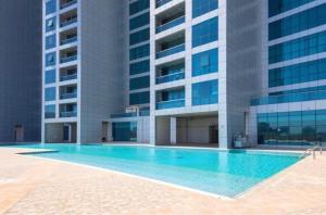 a swimming pool in front of a building at Walk to the Beach, Charming 3-Bedroom Home in Ajman Corniche Residences in Ajman 