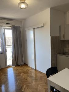 a living room with a kitchen and a wooden floor at Apartments Skako in Makarska