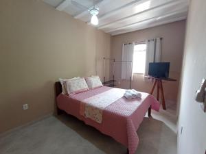 1 dormitorio con cama rosa y TV en LAGOA I - Saquarema RJ, en Saquarema
