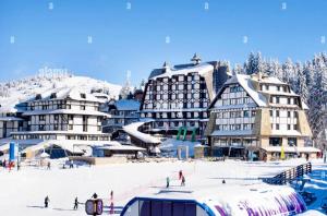 a group of people skiing in the snow in front of buildings at Apartment Marija- Kopaonik centar in Kopaonik