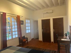 1 dormitorio con 1 cama, escritorio y ventanas en Chez Olivier - Île de Gorée, en Gorée
