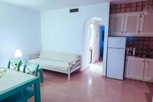a kitchen with a couch and a refrigerator in a room at Bord de mer & Piscine à Son Bou - Alaior / 4 pers in Alaior