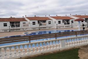 a white fence next to a swimming pool with buildings at Bord de mer & Piscine à Son Bou - Alaior / 4 pers in Alaior
