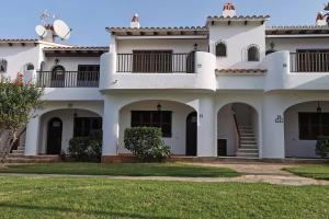 a white building with balconies and a yard at Bord de mer & Piscine à Son Bou - Alaior / 4 pers in Alaior