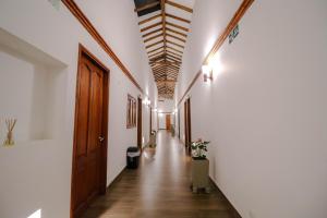 un pasillo con paredes blancas y techo de madera en Hotel las Palmas en Villa de Leyva