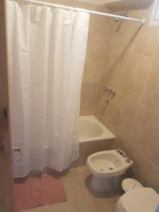 y baño con cortina de ducha blanca y aseo. en Departamento en Costanera en Gualeguaychú