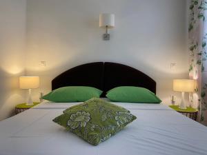 a bedroom with a bed with green pillows and two lamps at Secret Garden Apartment in Zadar