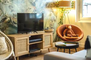 um urso de peluche sentado numa cadeira ao lado de uma televisão em SUITE JUNGLE - JARDIN, NETFLIX et PARKING - Le Manoir aux Pommes em Orbec-en-Auge