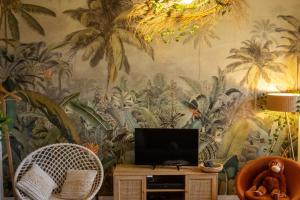 a living room with a wall mural of palm trees at SUITE JUNGLE - JARDIN, NETFLIX et PARKING - Le Manoir aux Pommes in Orbec-en-Auge