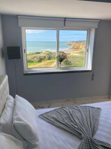 a bedroom with a window with a view of the ocean at SEA FRONT in Armação de Pêra