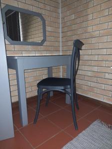 uma cadeira preta sentada debaixo de uma secretária com um espelho em Vita Nova em Bloemfontein