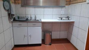 uma pequena cozinha com um lavatório e uma lata de lixo em Vita Nova em Bloemfontein