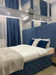 um quarto com uma cama grande e uma cabeceira azul em SpaNish apartman em Niš