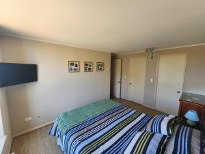 a bedroom with a bed and a flat screen tv at Departamento Laguna Vista in Algarrobo