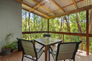 una mesa de madera y sillas en un porche cerrado en Hunchy Hideaway, en Montville