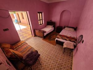 ein lila Zimmer mit 2 Betten und einem Stuhl in der Unterkunft Dar de l'Atlas in Lalla Takerkoust