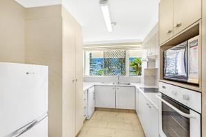 a white kitchen with a sink and a window at Cashelmara Burleigh - Hosted by Burleigh Letting in Gold Coast