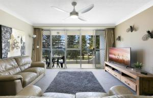 a living room with a couch and a flat screen tv at Cashelmara Burleigh - Hosted by Burleigh Letting in Gold Coast