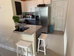 a kitchen with a stainless steel refrigerator and two white stools at Starr & Adams Caribbean Oasis in Point