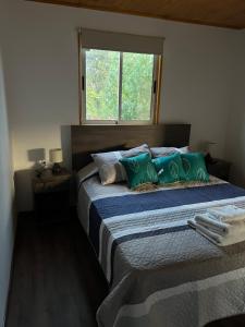 Un dormitorio con una cama con almohadas verdes y una ventana en Hostería Estelita en Panimávida