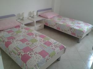 two beds with pink and green quilts in a room at Apartments MiaMaja in Novalja