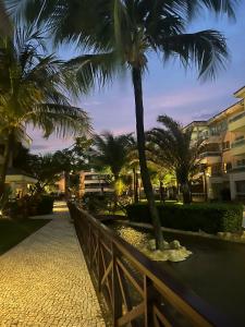 uma passagem com palmeiras e uma cerca em Apartamento Breezes do Cumbuco - TÉRREO o famoso pé na areia em Cumbuco