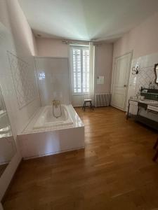 Großes Zimmer mit Badewanne in einem Zimmer mit Holzboden in der Unterkunft Domaine de Pladuc in Lachaise