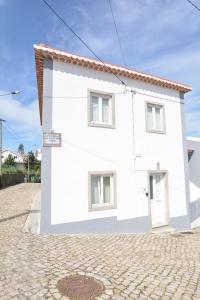 ein weißes Haus in einer Kopfsteinpflasterstraße in der Unterkunft Casa da Fonte in Sintra