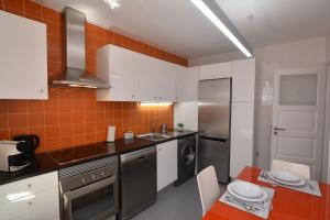 uma cozinha com armários brancos e uma parede de azulejos laranja em Casa da Fonte em Sintra