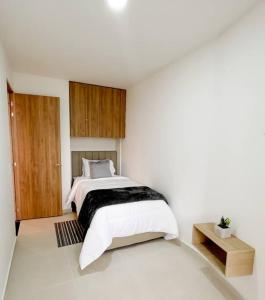 a white bedroom with a bed and a wooden door at 202S Encantador apartamento para ti! in Ibagué