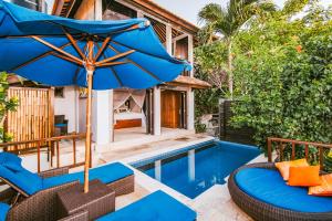 un patio con sillas y una sombrilla junto a la piscina en Villa Mimpi Manis, en Nusa Lembongan