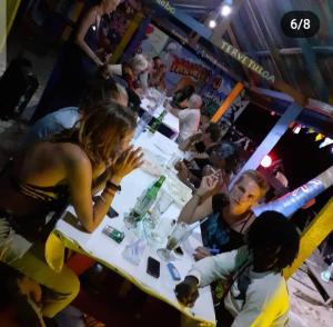 un grupo de personas sentadas en una mesa en un bar en Kangaroo Pouch Beach Resort, en Busua