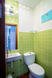 Baño de azulejos verdes con aseo y lavamanos en Trendy Homes Casa Nerida, en Rodalquilar