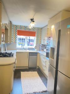 cocina con nevera, fregadero y ventana en A Perfect Two Bedroom House for a Family Stay, en Havering atte Bower