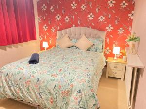 a bedroom with a bed with a flower patterned wall at A Perfect Two Bedroom House for a Family Stay in Havering atte Bower