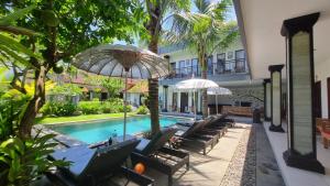 a pool with chairs and umbrellas next to a building at Surf Lodge Canggu in Canggu