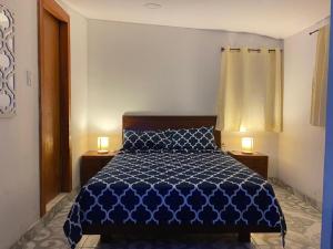 a bedroom with a blue bed with two lamps on tables at Miss Titi's Native Lodge in San Andrés